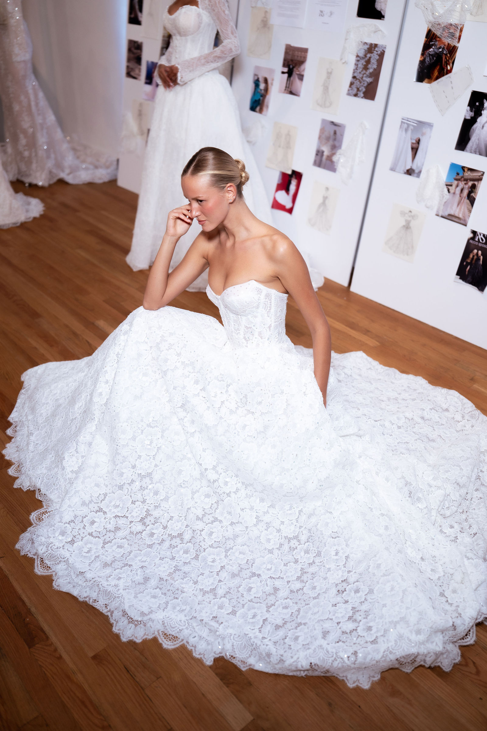 A model in a lace ball gown from the 2028 collection, its skirt pooled across the gallery floor